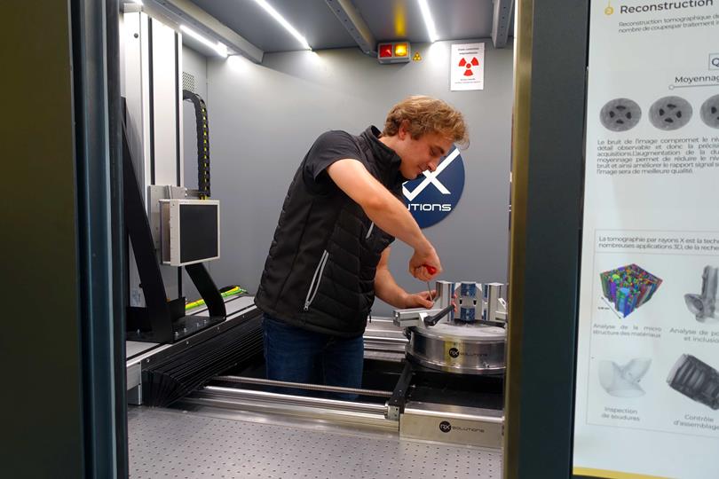 Cyril de l'équipe Prestation installe un support d'échantillons dans un tomographe chez RX Solutions